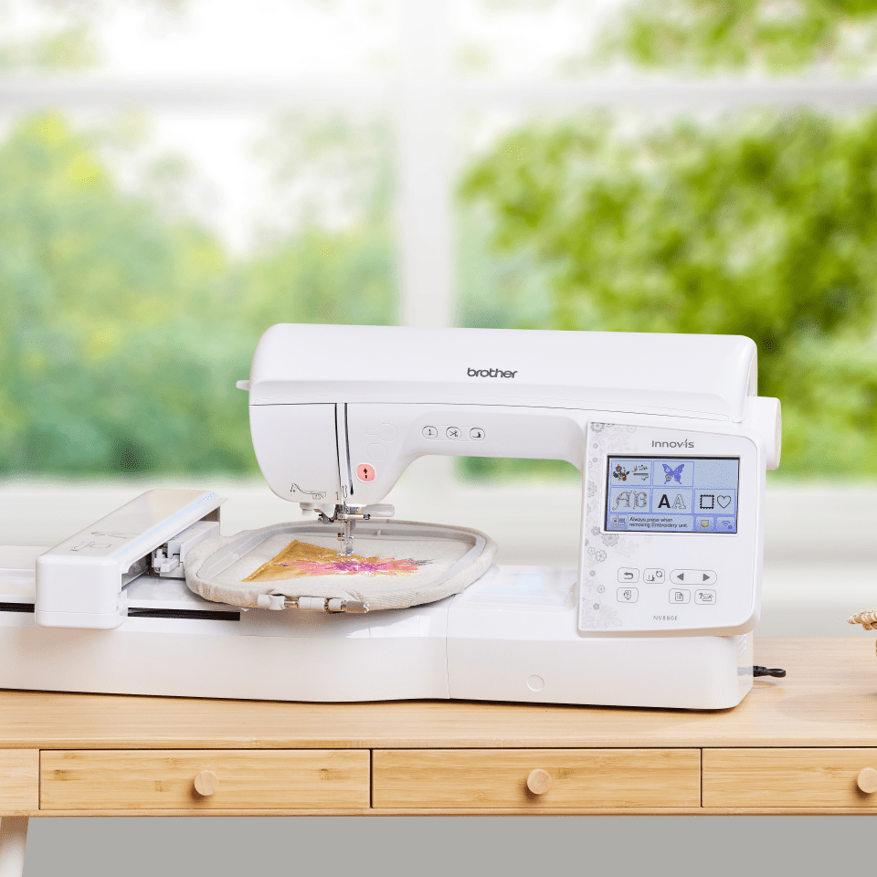 nv880e on a table with embroidery hoop & design