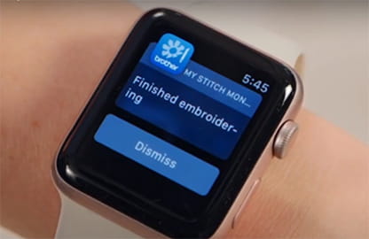 Image of a smart watch displaying a message from the Brother My Stitch Monitor app notifying that the machine that is linked  has 'Finished embroidering'