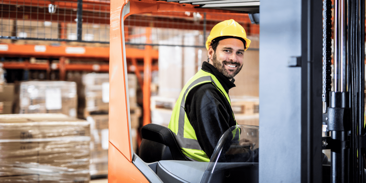 A warehouse worker in a forklift driving.