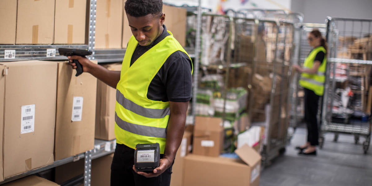 A warehouse worker with a mobile label printer scanning stock