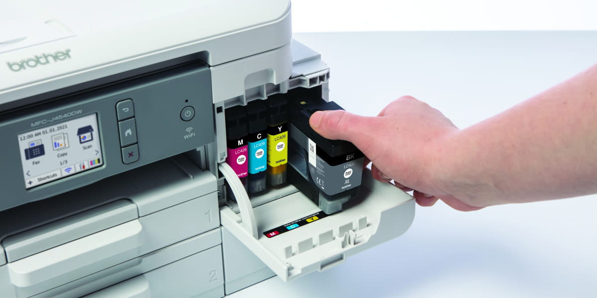 A hand opening a Brother inkjet printer and pulling out the black ink cartridge