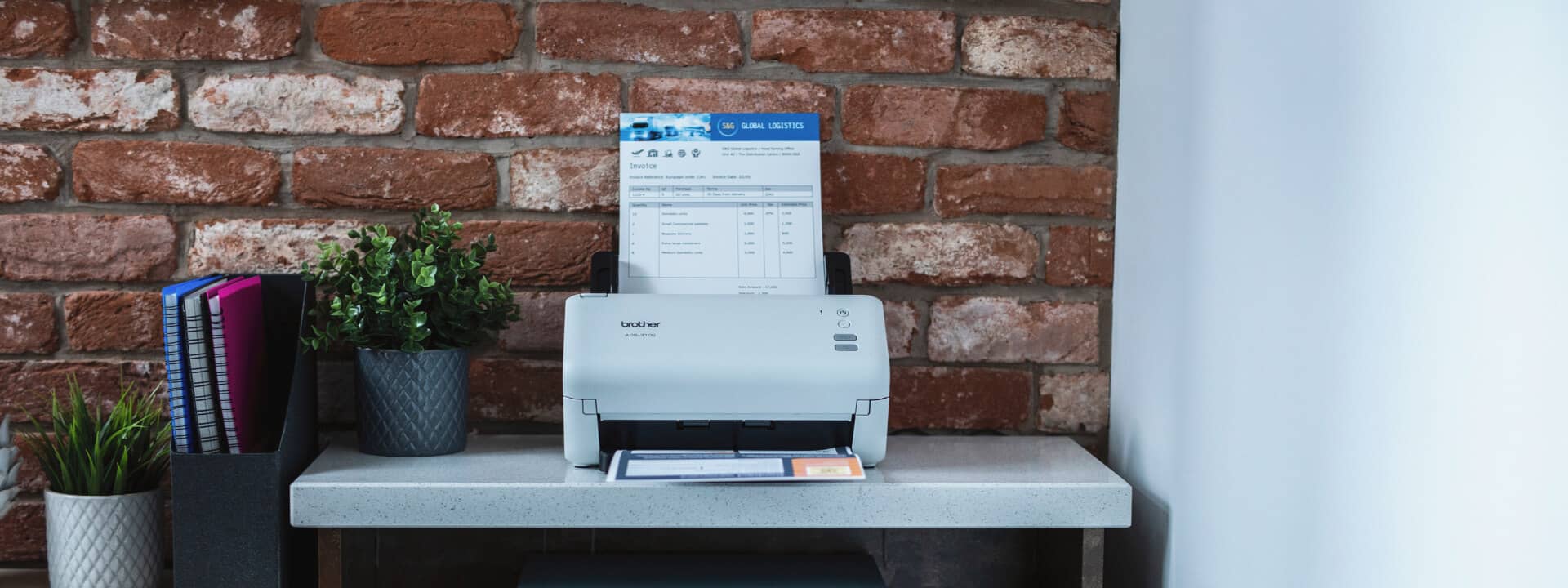 A Brother document scanner ADS-3100 in a home office setting scanning a document