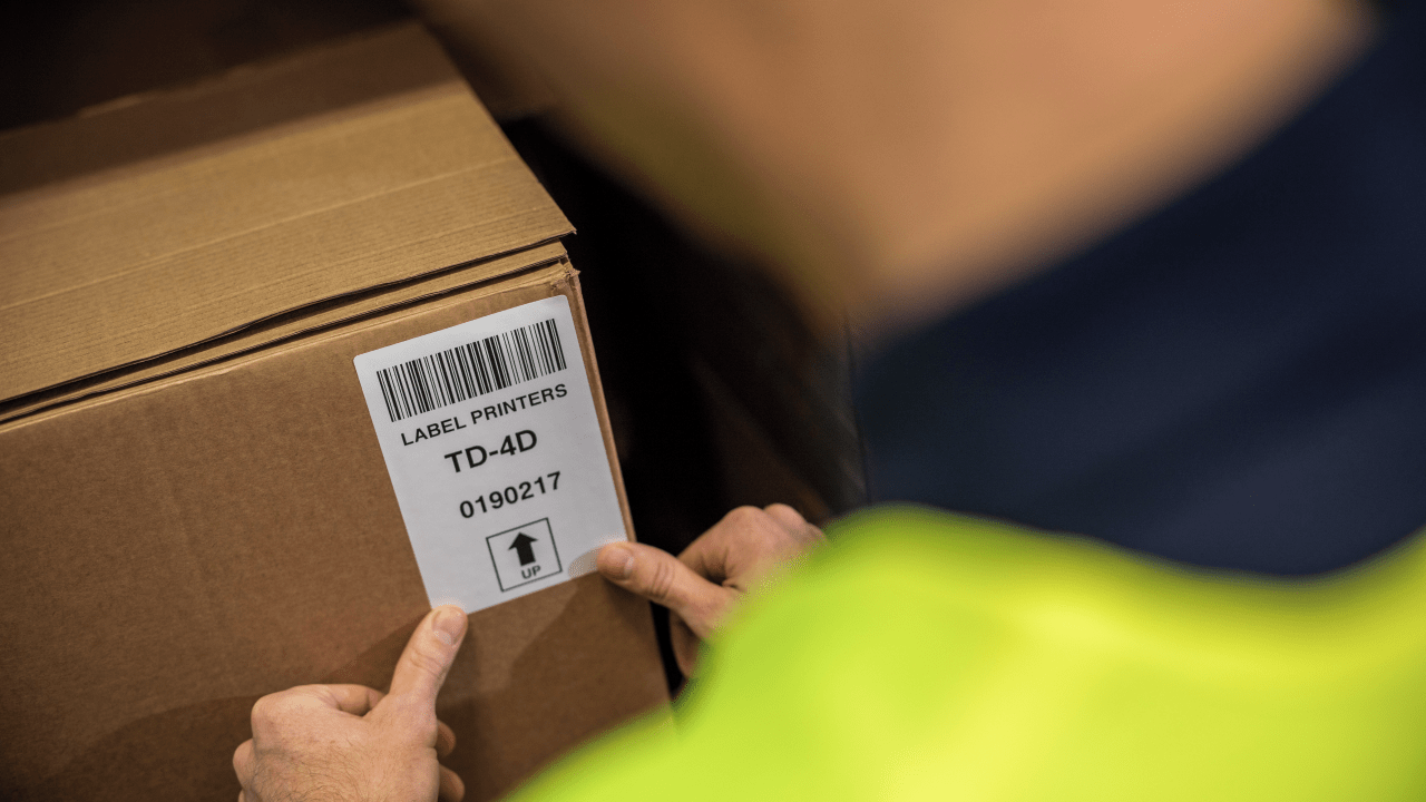 Man placing a barcode label onto an item of stock in a warehouse. 