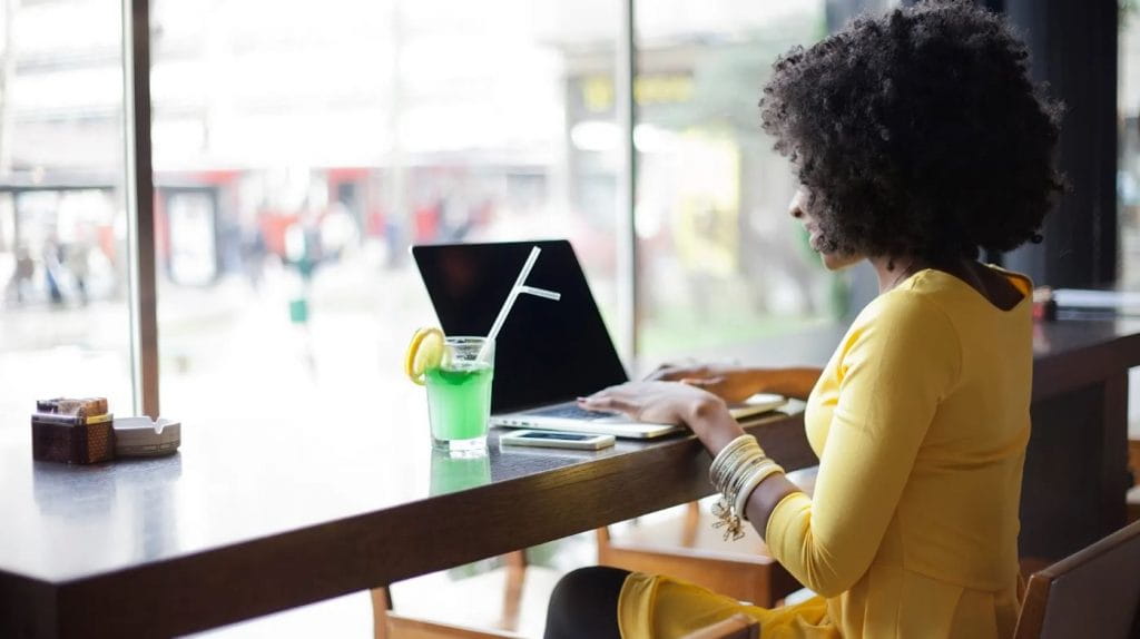 A lady using a laptop in a cafe with a drink