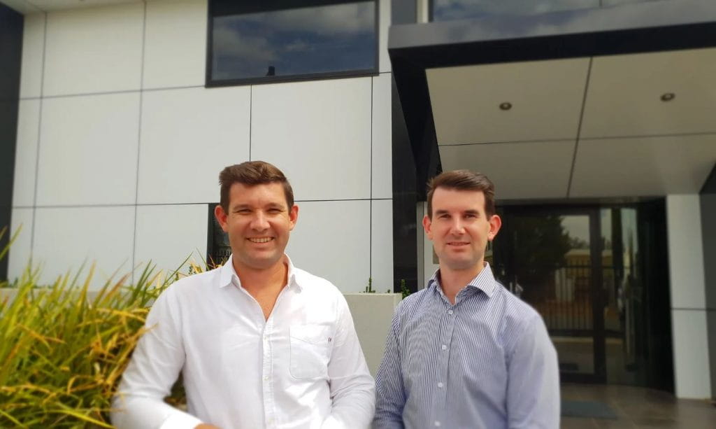 Craig and Phil Suggate standing in front of a building