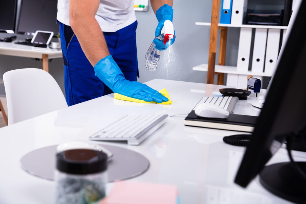 An office worker disinfecting his workstation and computer.