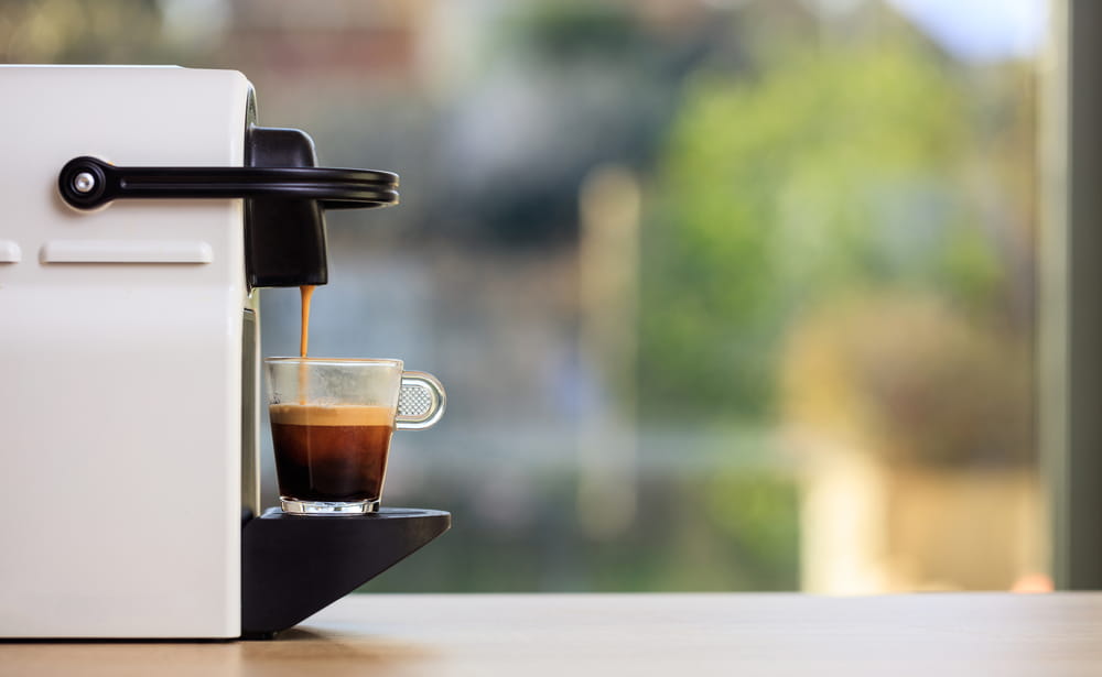 A coffee machine pouring into a clear cup.