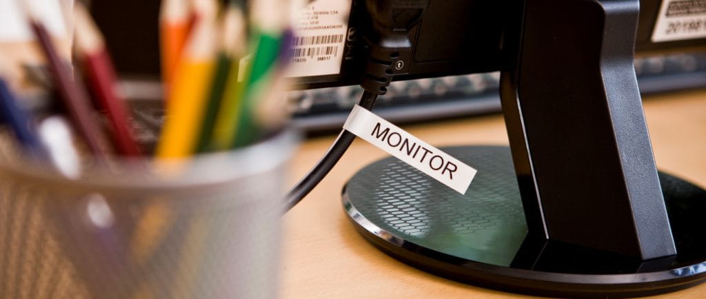 A computer monitor with a label around the cord.