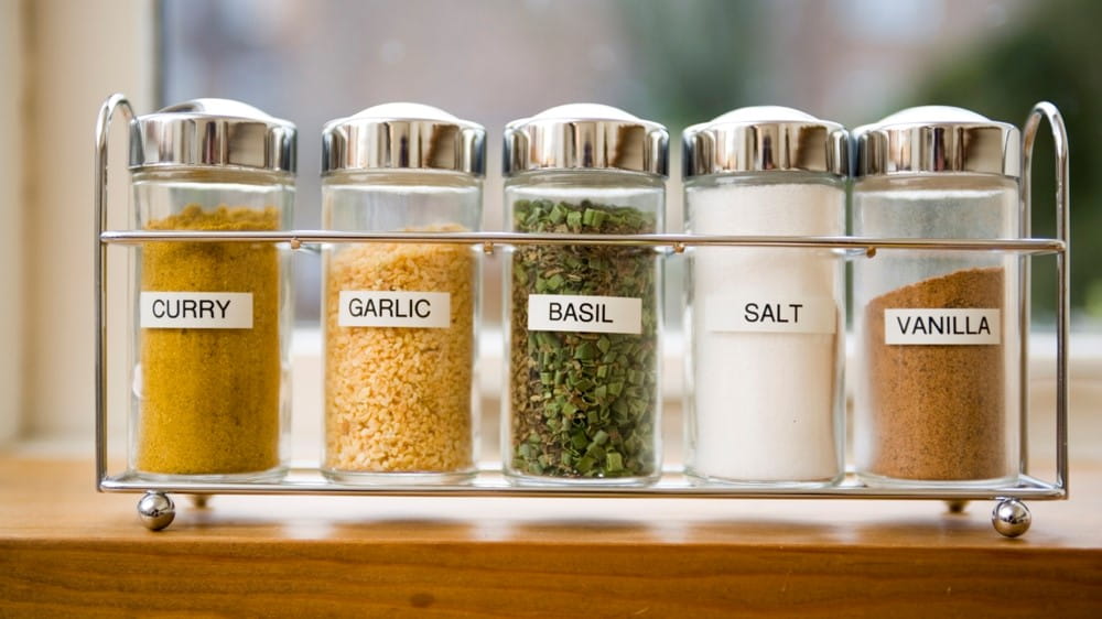 A bunch of kitchen spices and herbs with labels on them.