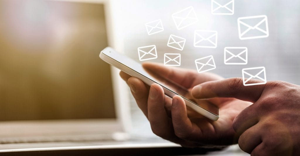 A person holding a smartphone with email icons around it.