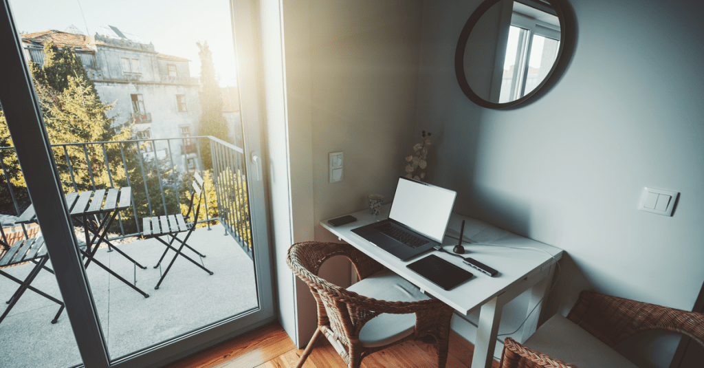 A neat and small study nook with natural light and a laptop on a desk with two chairs.