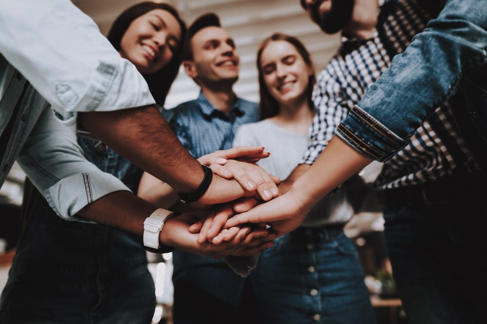 A group of young employees placing showing unity at work.