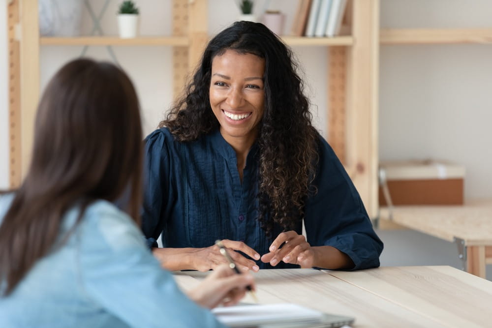 Two female workers communicating and collaborating happily in the office.