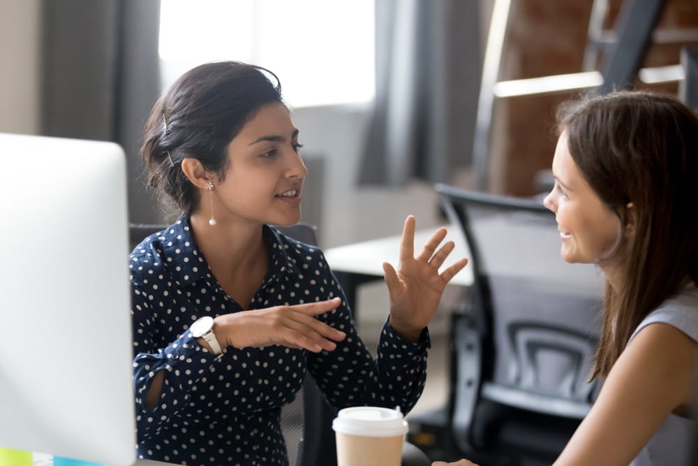 Two female workers enjoying a conversation while on a break at work.