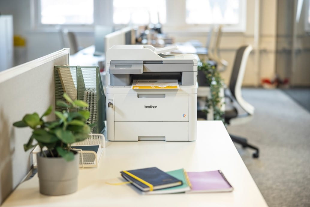 A Brother compact laser multifunction printer in a small office setting