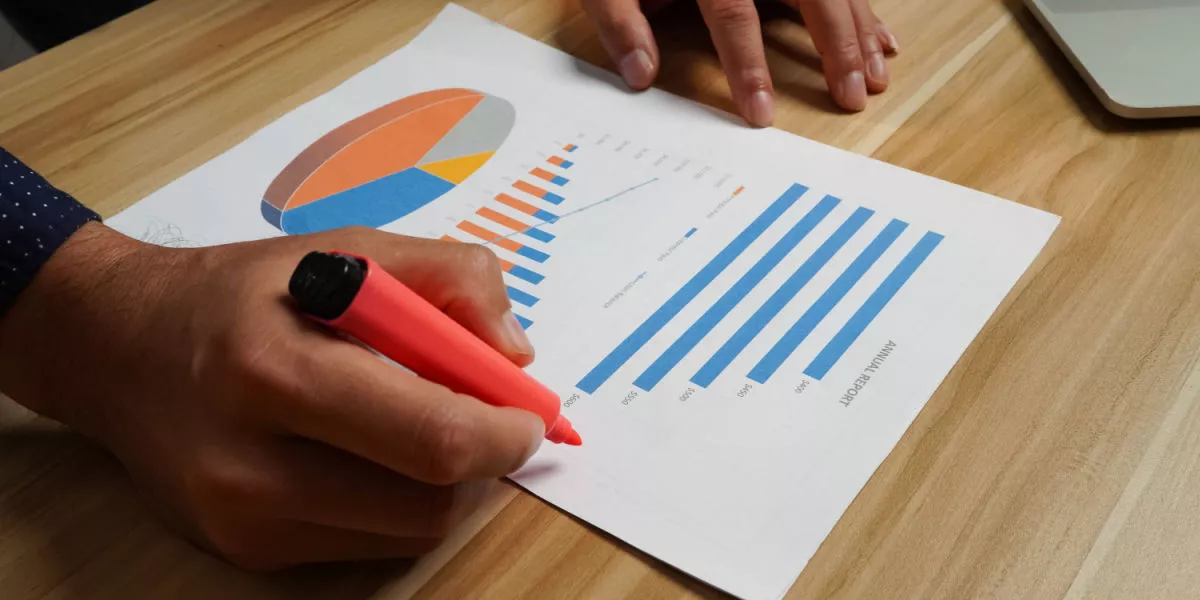 Office worker hands highlighting a chart with graphs of sustainable goals.