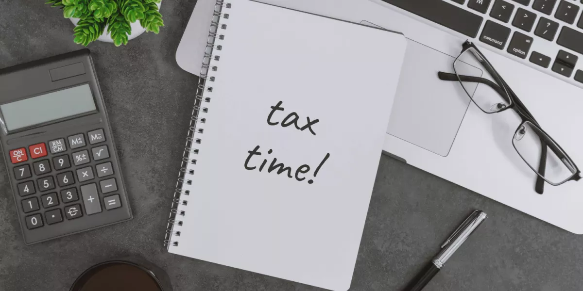 Tax time written on a notepad next to a calculator and glasses