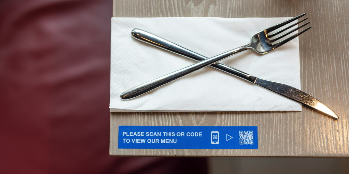 A QR code on a dining table in a restaurant next to cutlery 