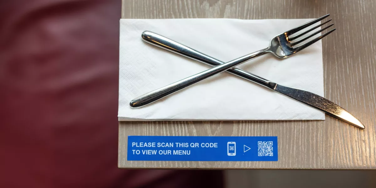 A QR code on a dining table in a restaurant next to cutlery
