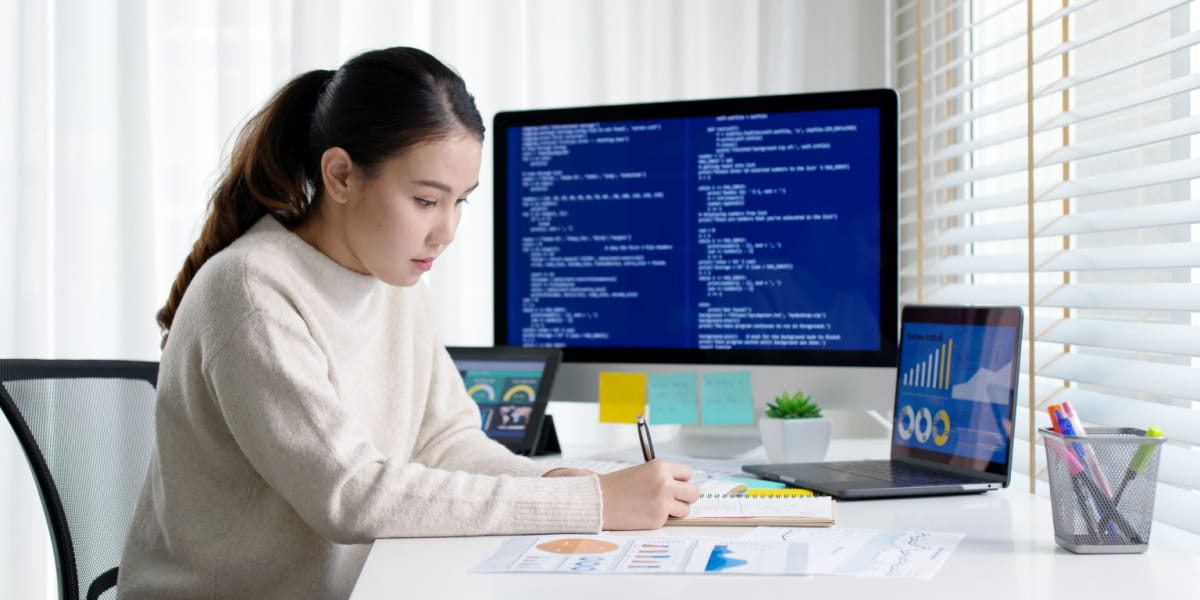 Lady working from home with multiple screens and documents on the desk
