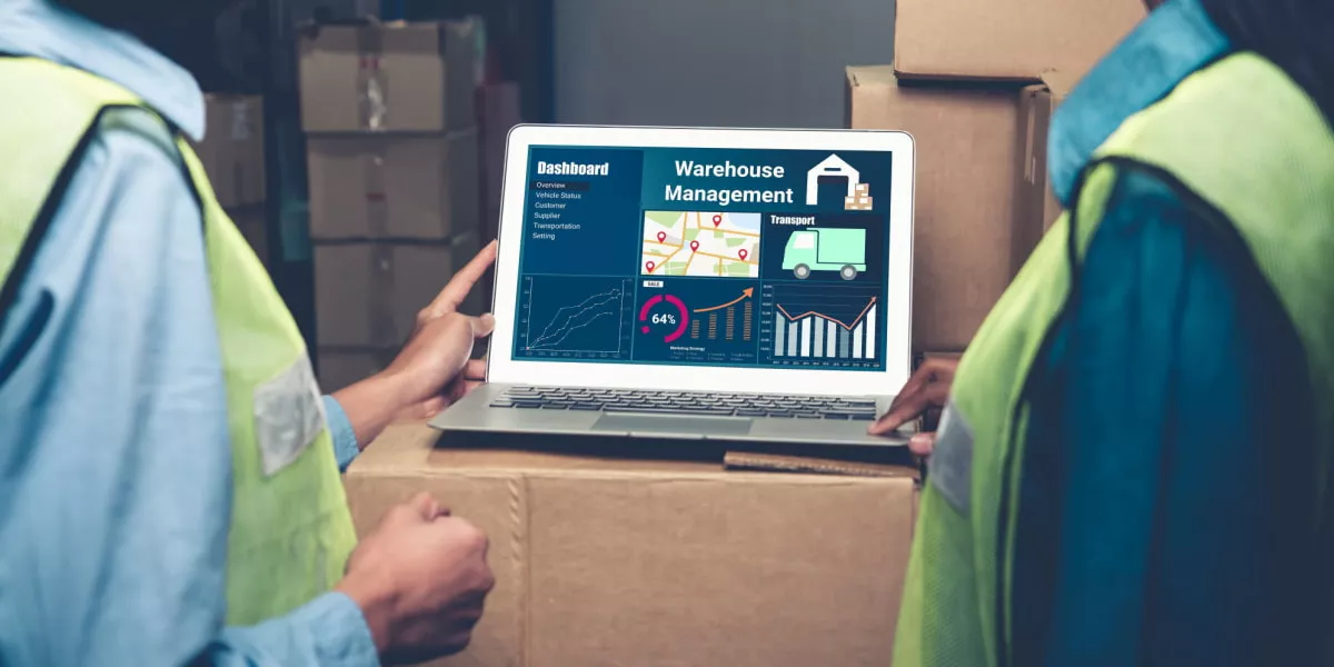 Two warehouse workers looking at a screen next to stock