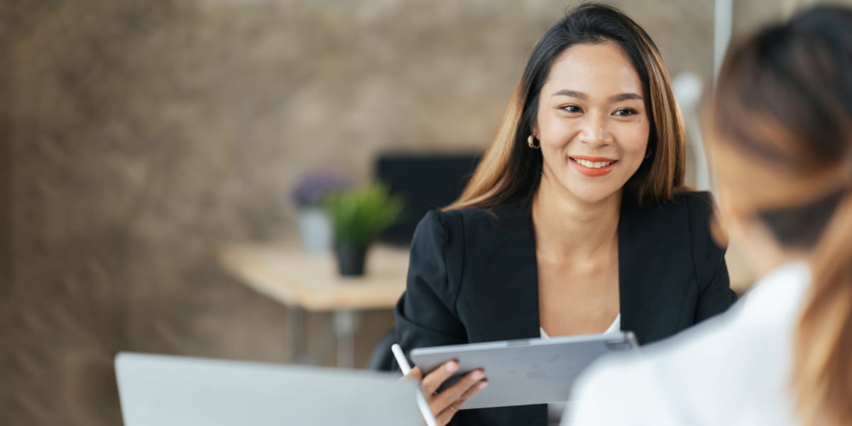 Two colleagues sharing a positive conversation with laptops in hand