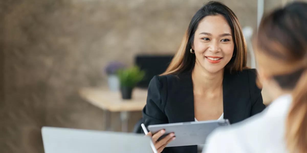 Two colleagues sharing a positive conversation with laptops in hand