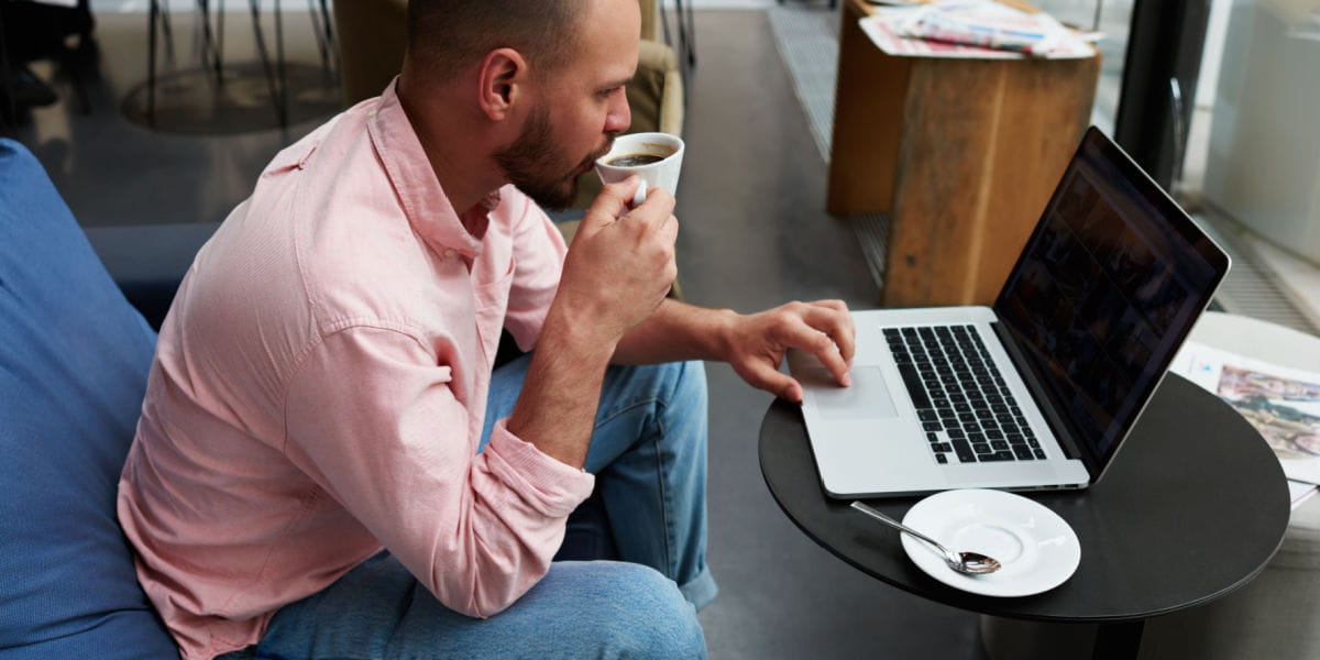 Man sitting down working on a laptop with a coffee