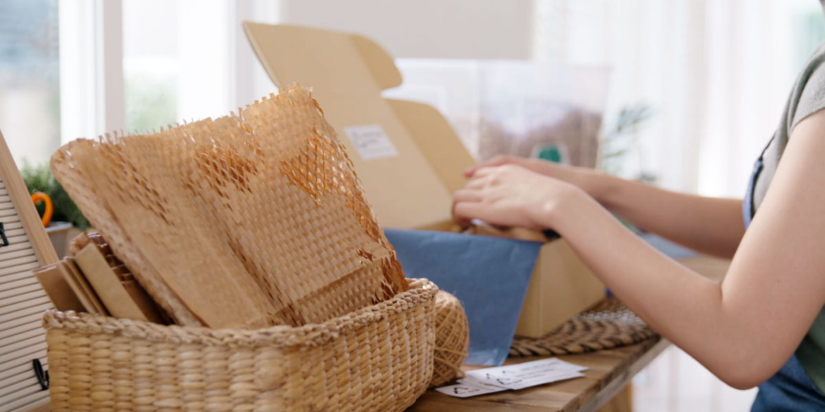 An e-commerce owner packing orders using sustainable packaging. 