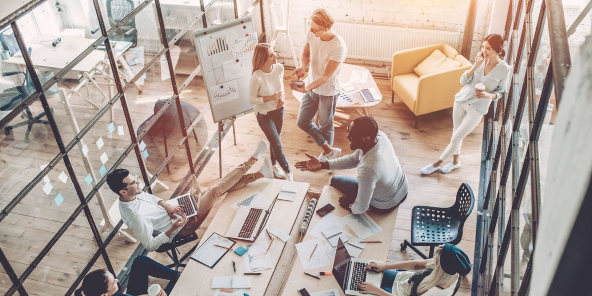 A modern office with a team collaborating over hybrid furniture. 