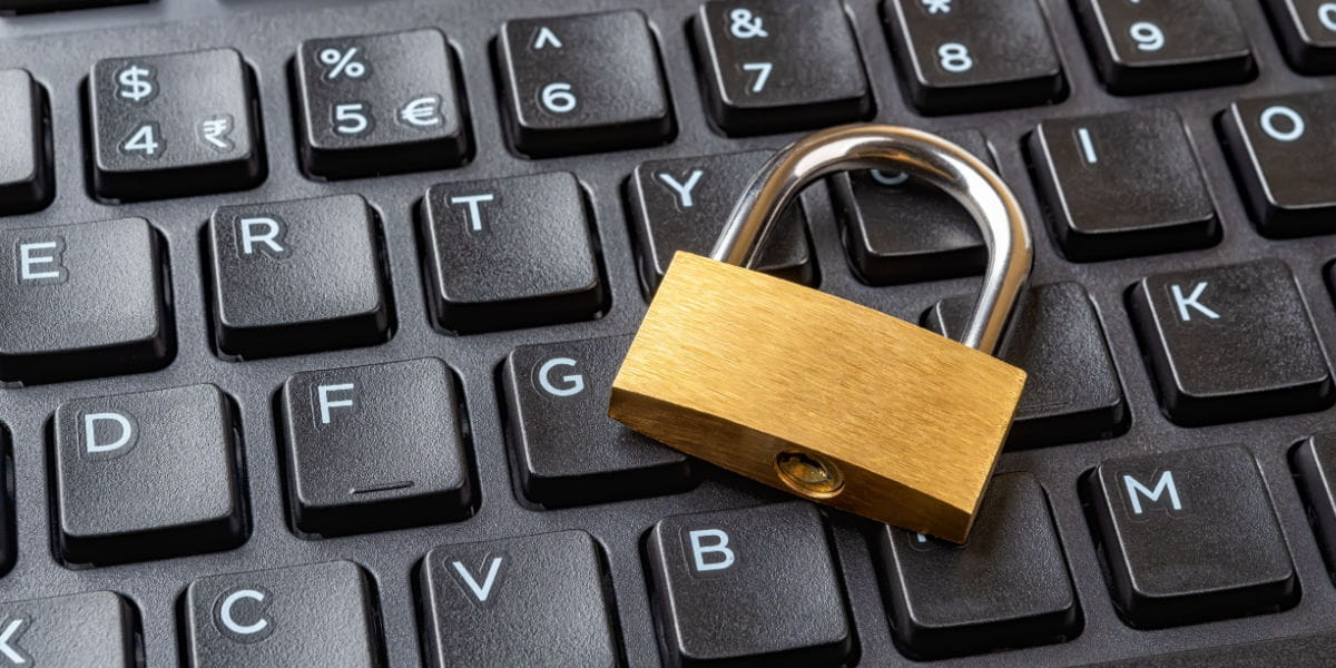 A gold padlock on a black keyboard depicting cyber security.