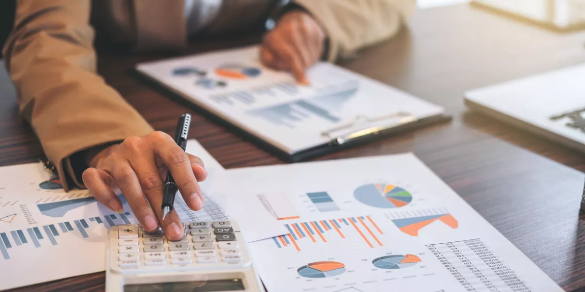 A person with a pen in hand pointing to multiple printed graphs