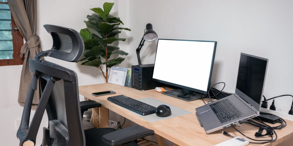 An ergonomic chair and height adjustable desk with a laptop and screen. 