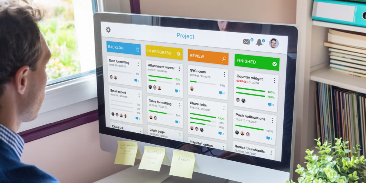 Man working on computer with several tasks visible on his screen