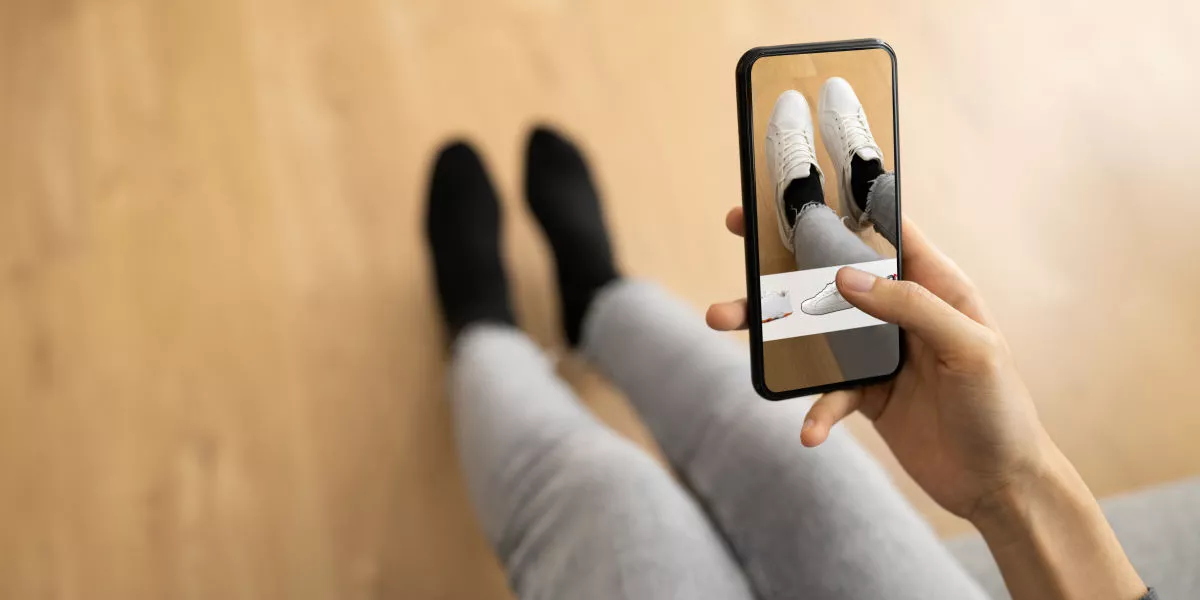 A person pointing a smartphone to their shoes depicting augmented reality