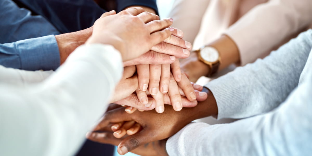 A group of employees placing their hands on top of one another depicting unity and support