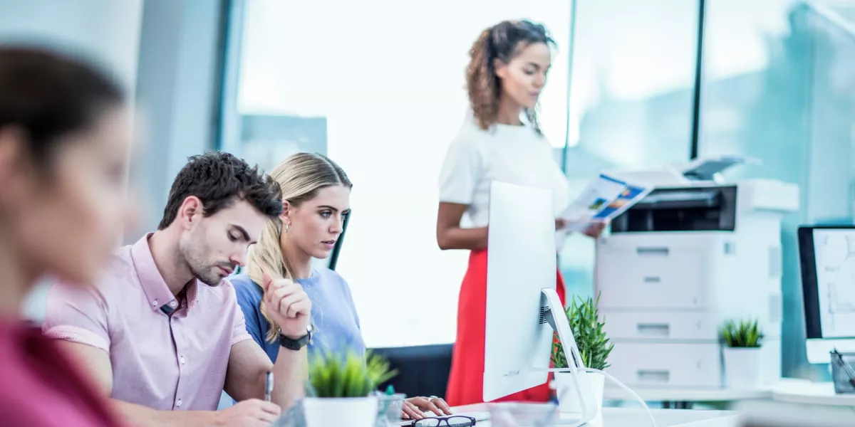 An office with lots of professionals next to a print station