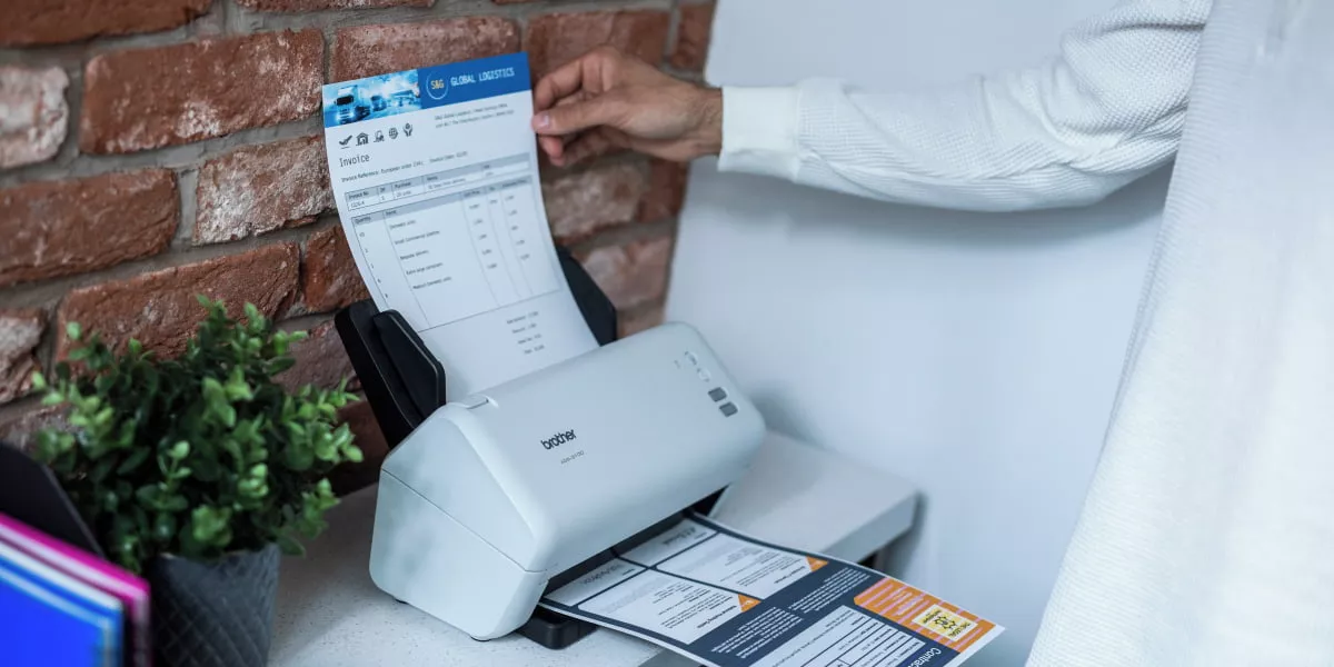 A person feeding a document into a Brother document scanner