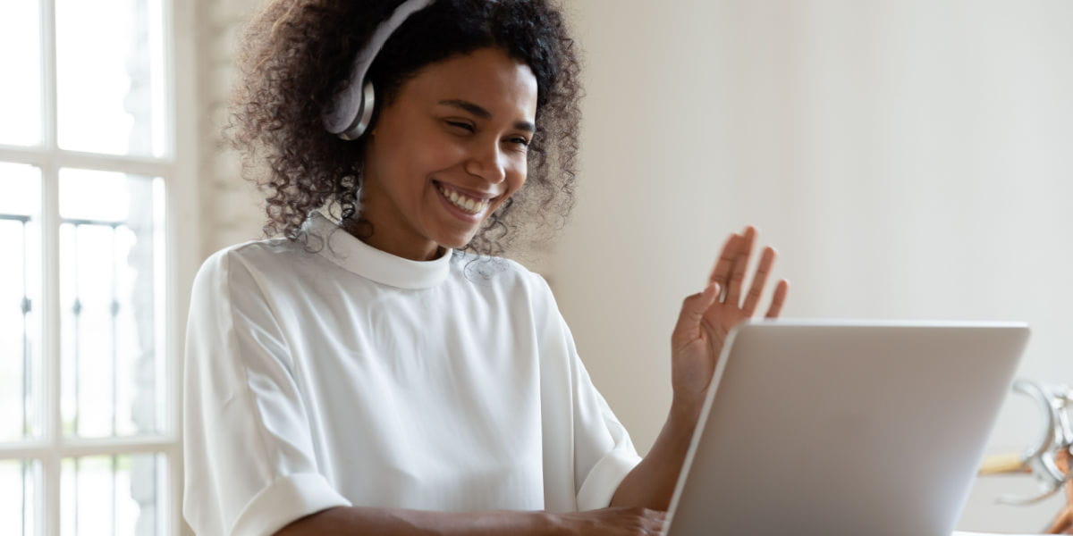 Lady smiling on laptop with headset during an online interview 
