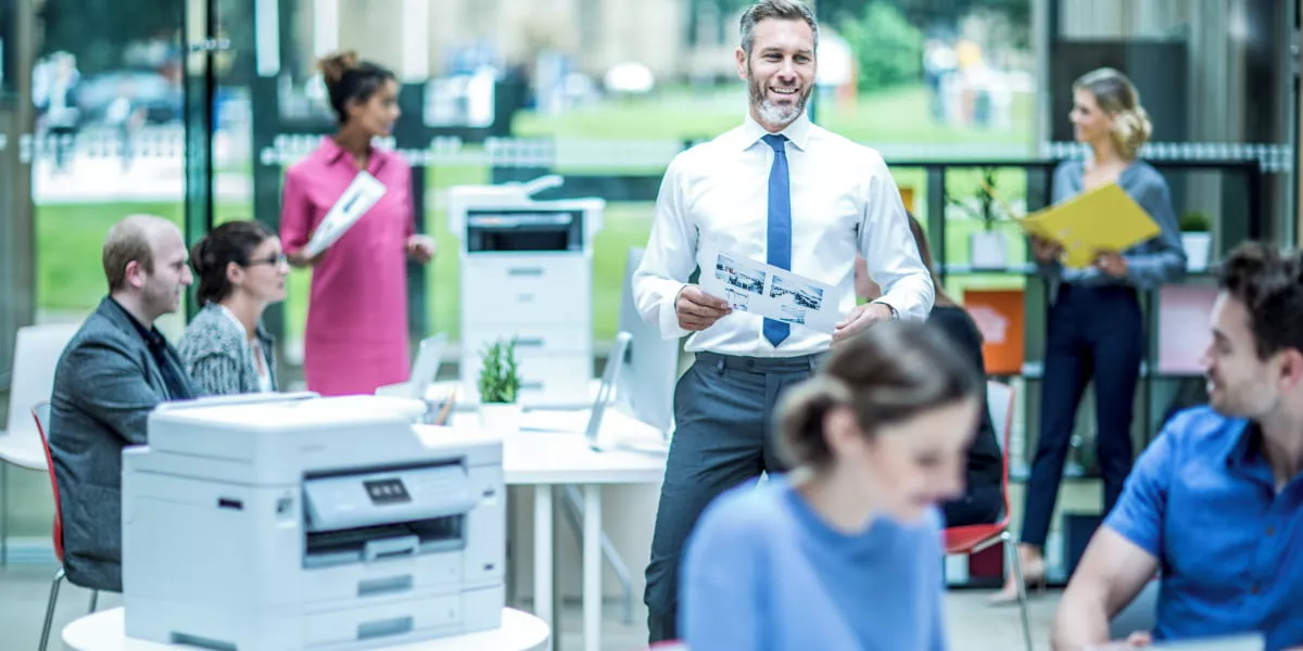 A busy office setting with a business inkjet printer front of screen