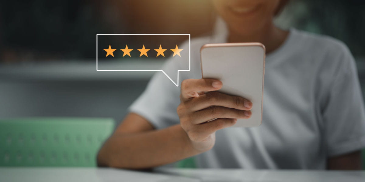 Person holding smartphone with stars visible depicting consumer reviews