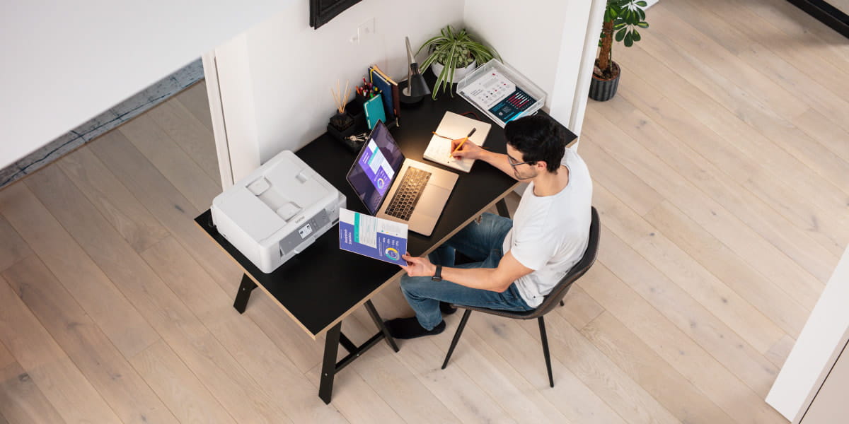Man working from home in a modern home office setup with a printer and laptop