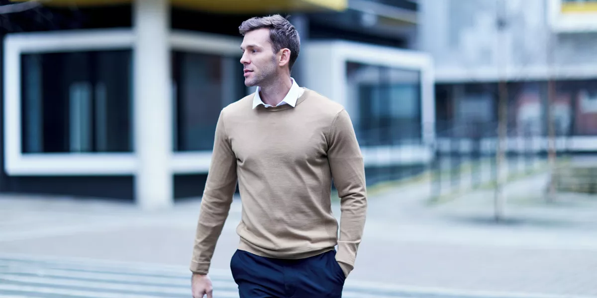 A male office worker walking across the street