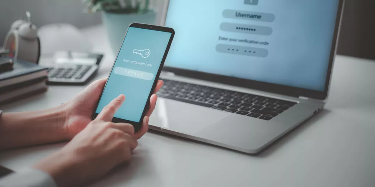 Hands with a smartphone in front of a laptop making a secure online payment.