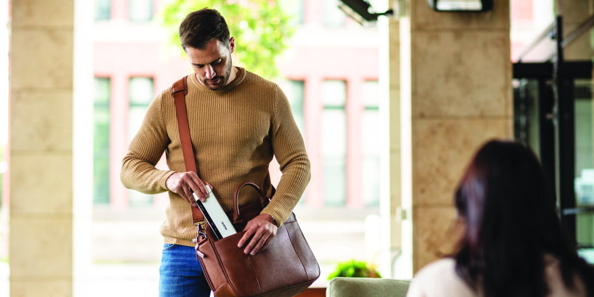 A man placing a portable scanner in his workbag in front of a receptionist