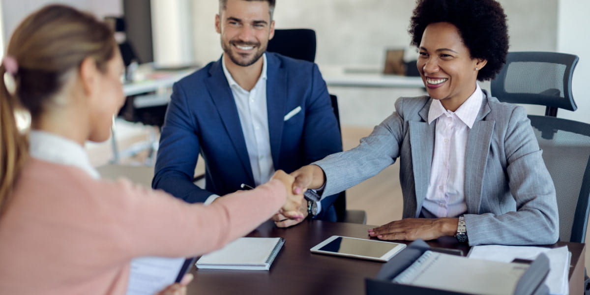Two HR workers shaking the hand of a candidate in an office meeting room