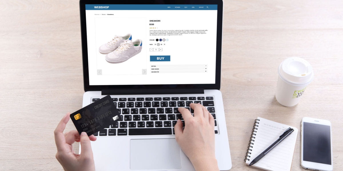 Hands on a laptop keyboard with a credit card buying shoes online.