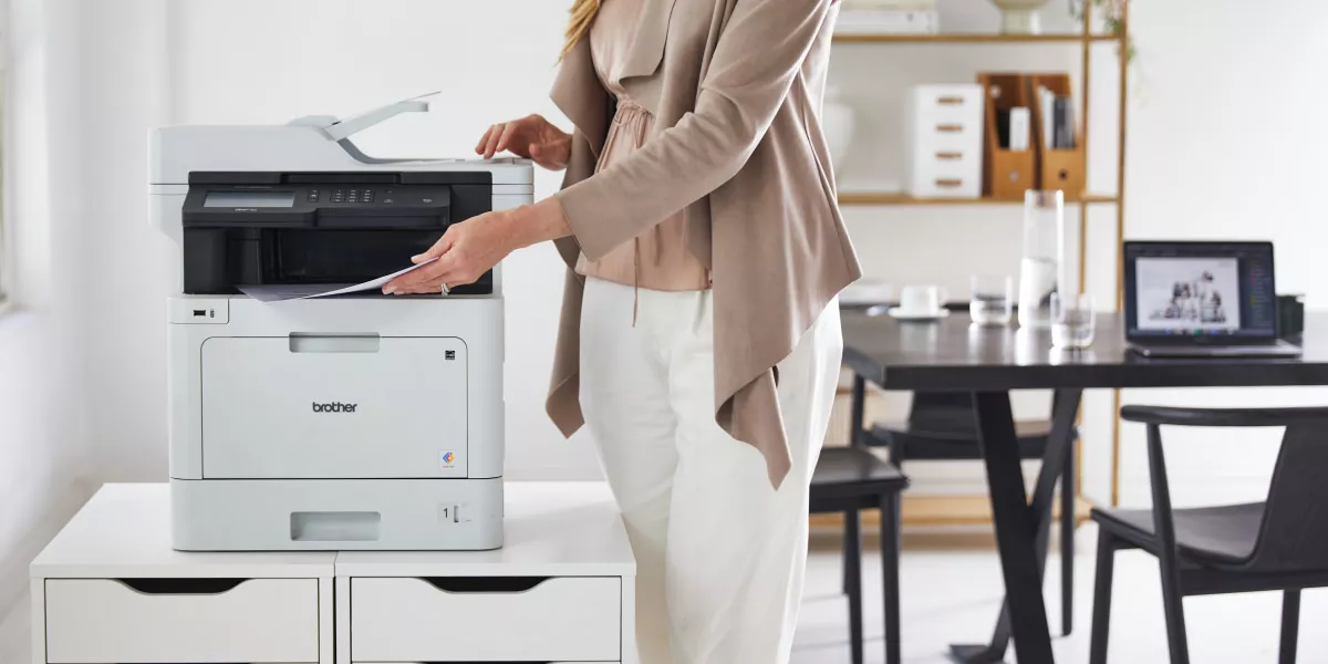 A Brother multi-function printer MFC-L8900CDW with a lady printing in office