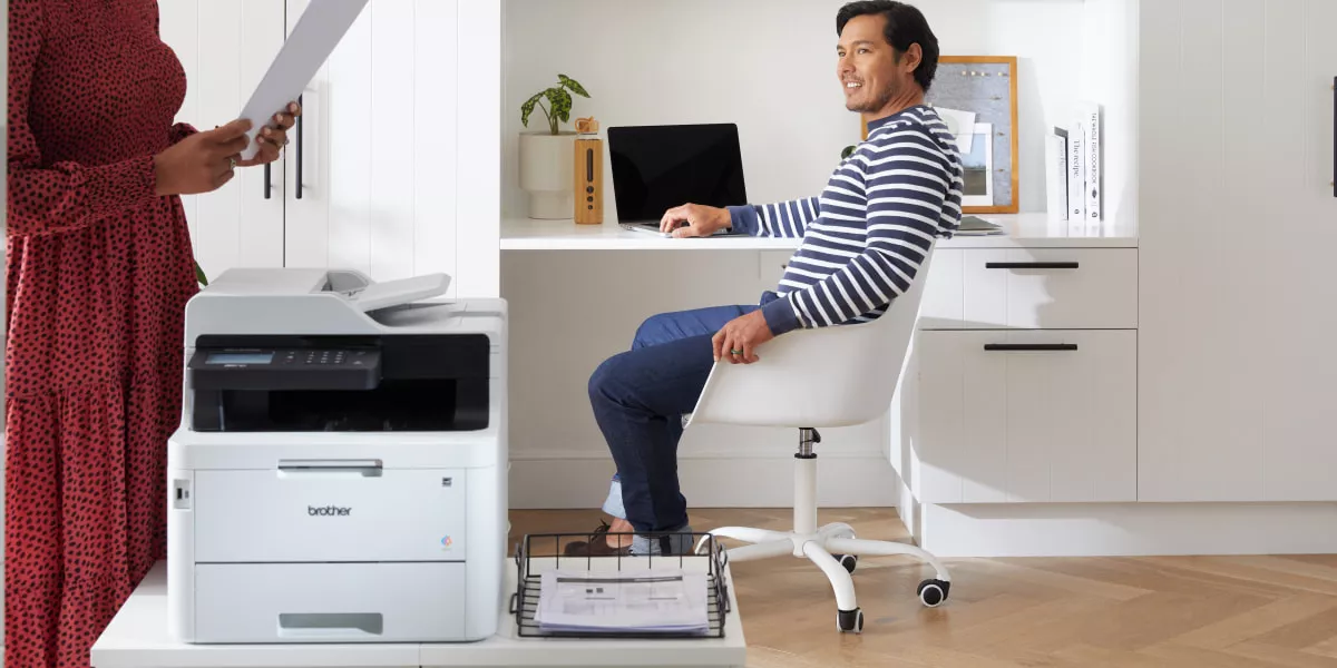Two workers printing out documents on a Brother Multi-Function Centre for their marketing tasks