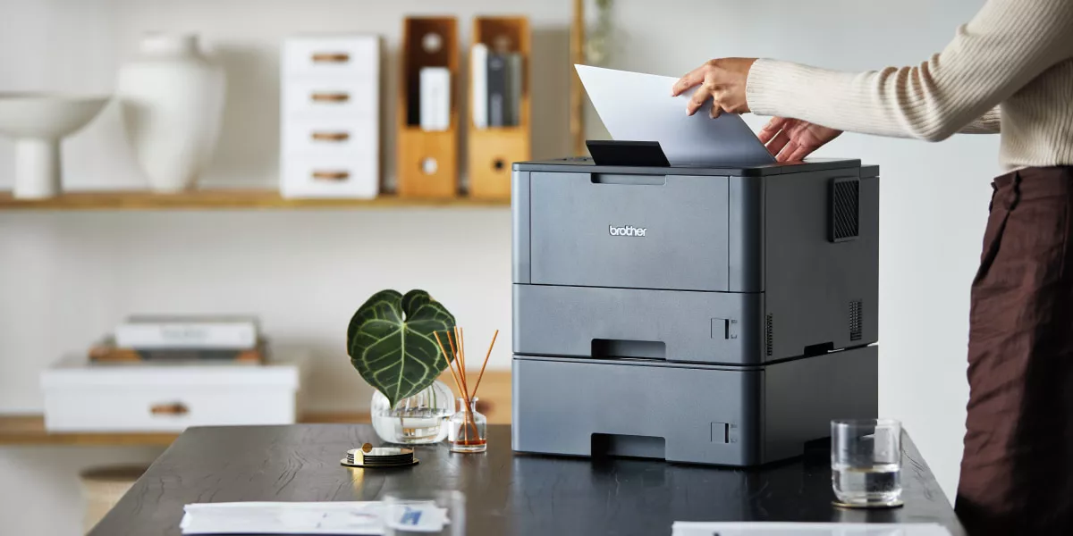 A Brother monochrome printer with a lady printing sustainably